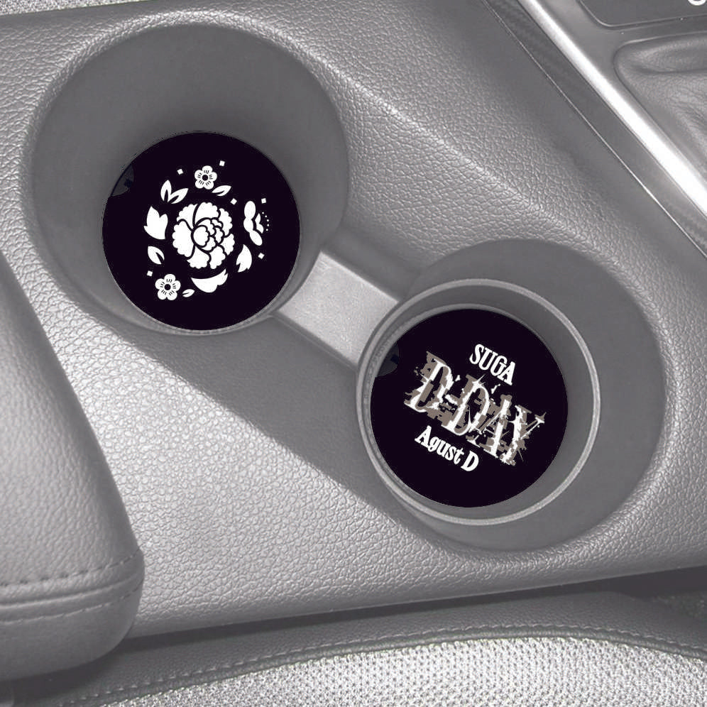 A set of black round Car Coasters with a divit on the left site. One coaster has Flowers and the other reads Suga D-Day Agust D.