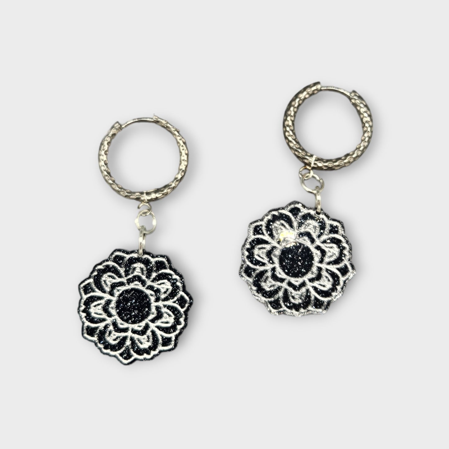 Hoop earrings with black glitter Flowers attached to them.