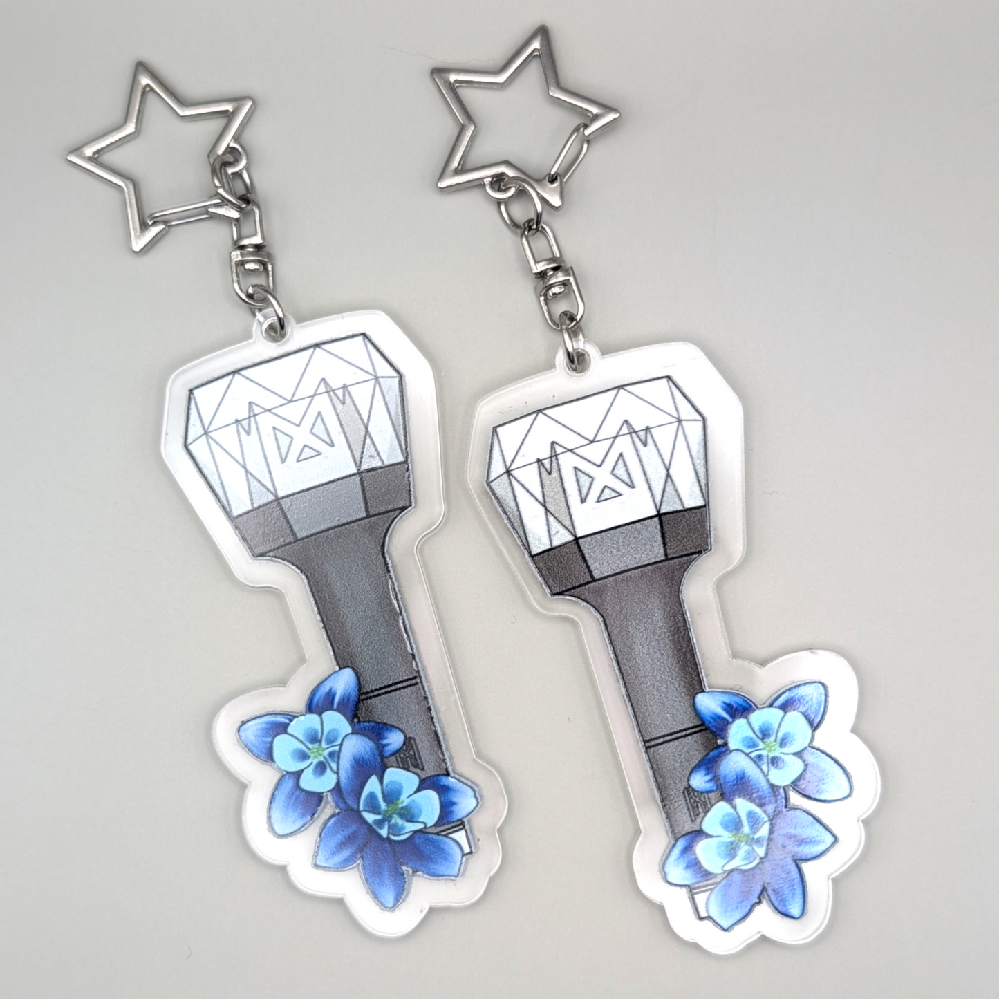 Monsta X lightstick with two blue flowers on the bottom. The silver keyring is star shaped.